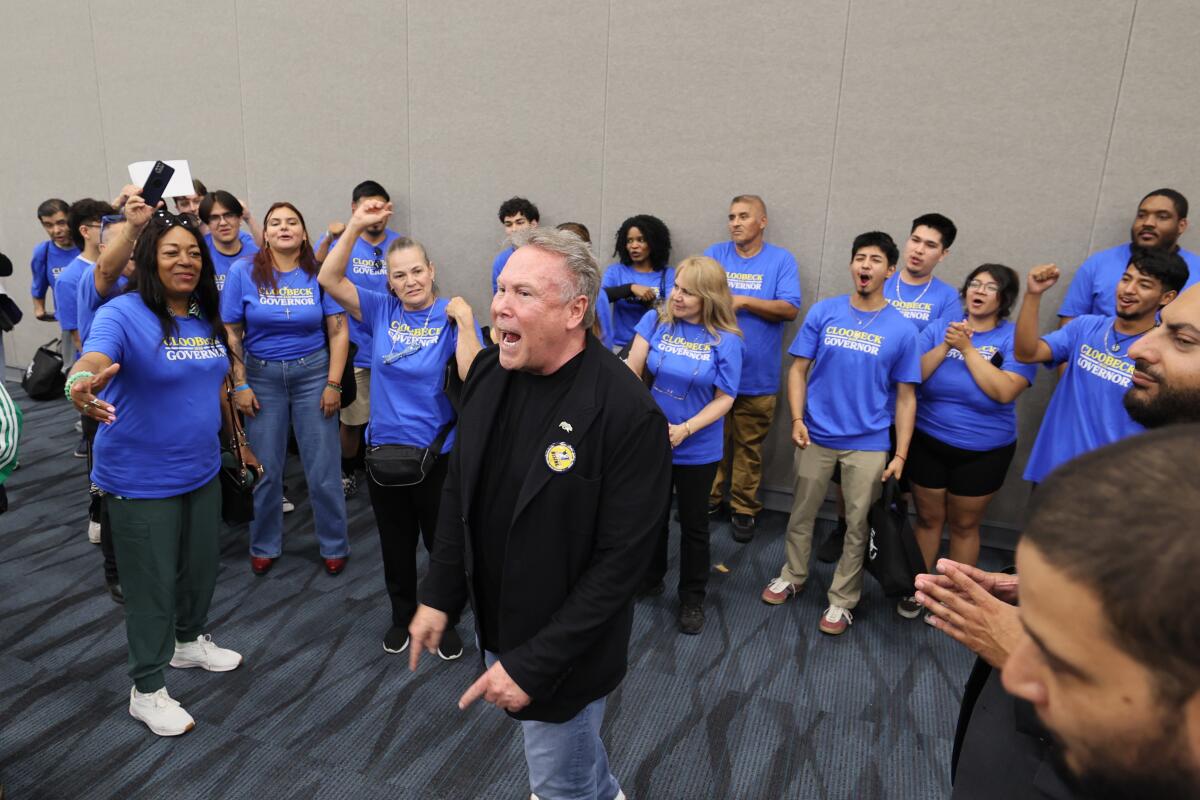 Stephen Cloobeck, in a black jacket, stands with canvassers wearing blue shirts.