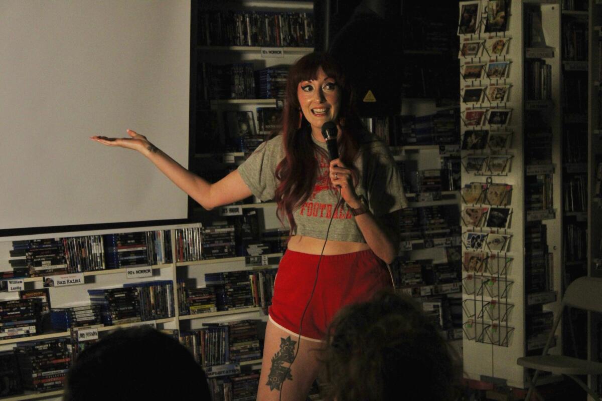 A person standing before an audience with a microphone.