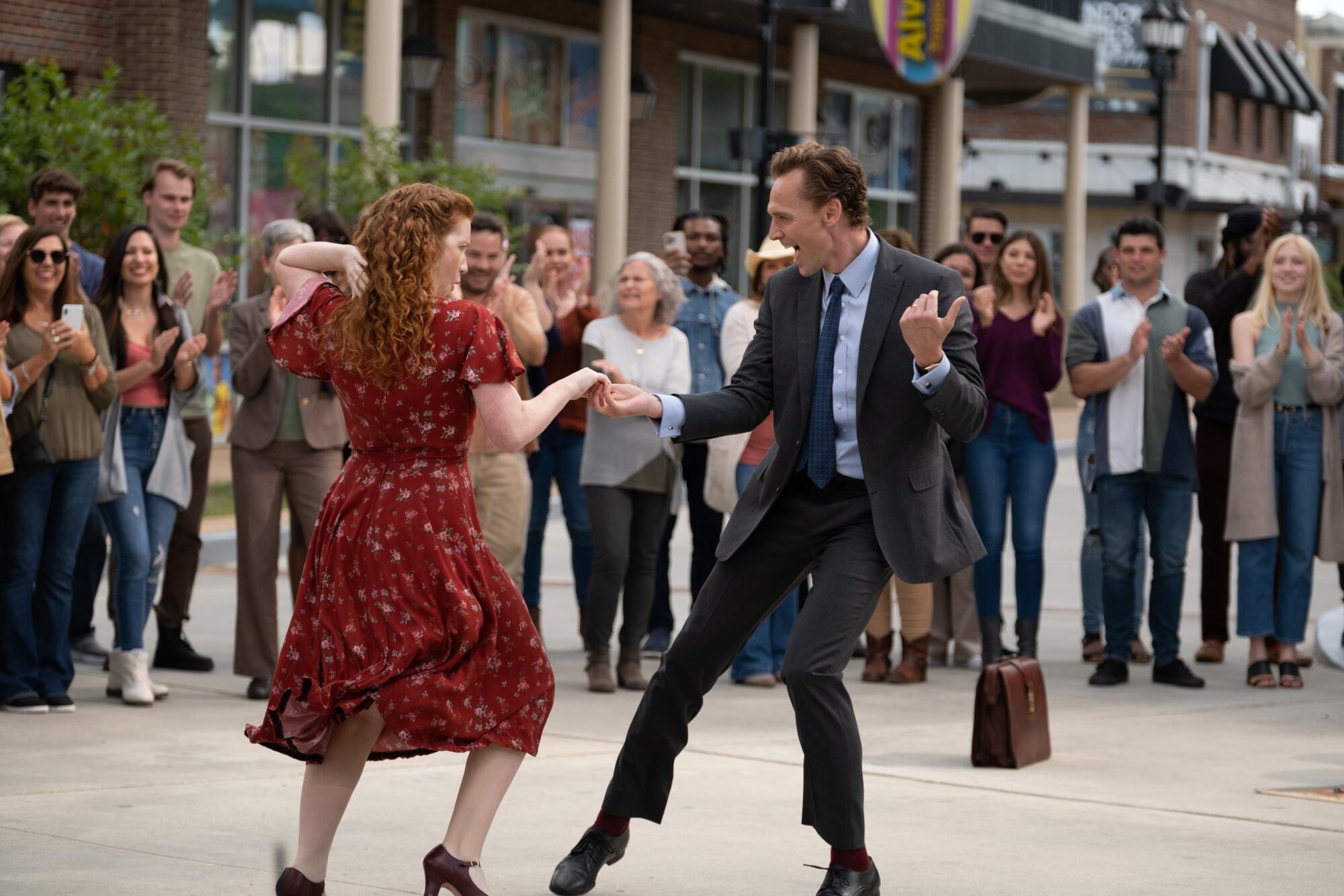 Two people dance happily in the street.