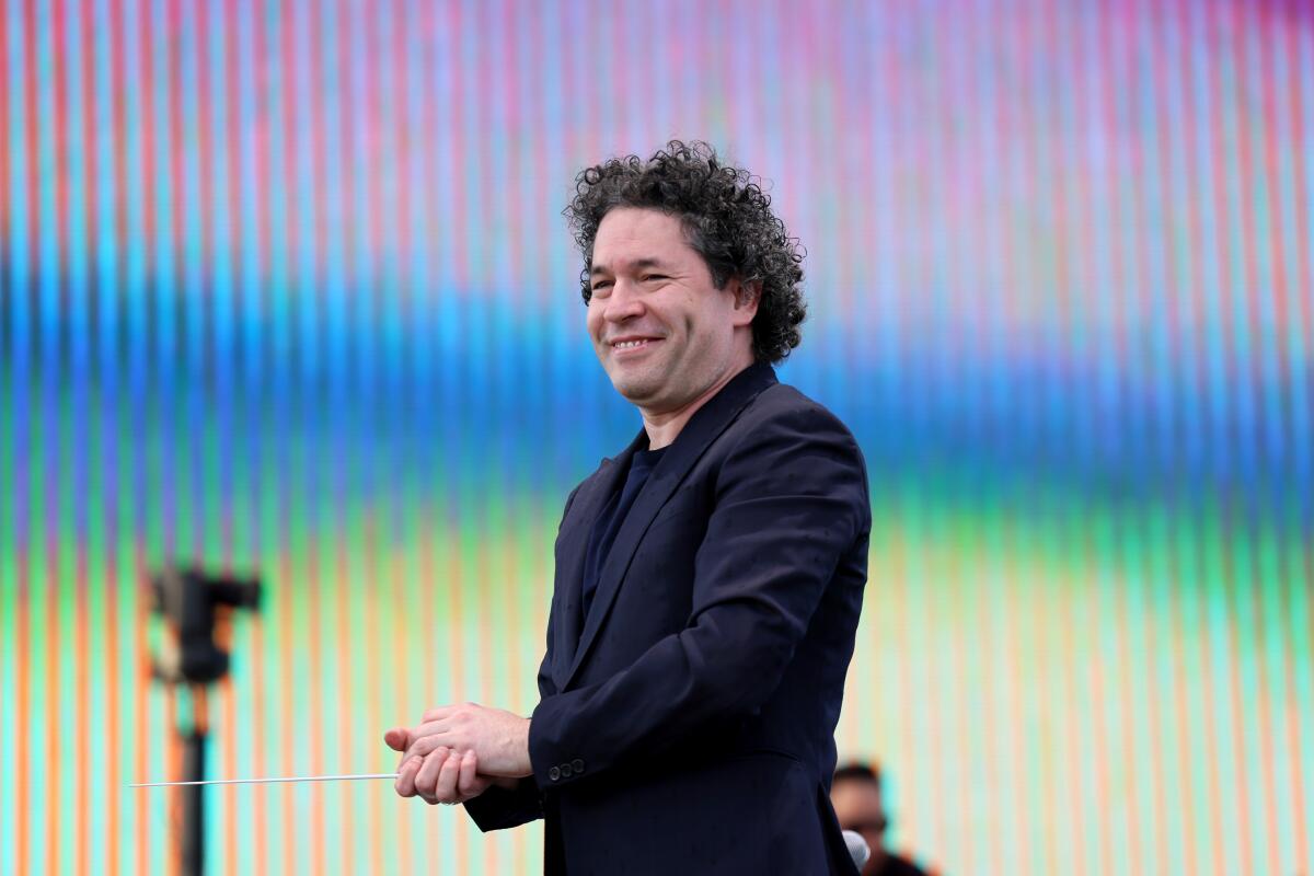 Gustavo Dudamel stands in front of a multihued video screen at Coachella.