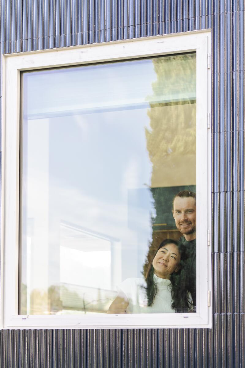 Vivian Mo and Michael Trobisch peek out the window of their home