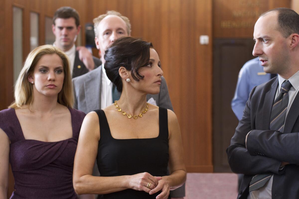 A man and a woman talk while others look on.