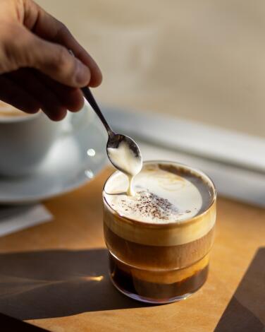 Dipping a spoon into a cup of Cream Top coffee at Maru