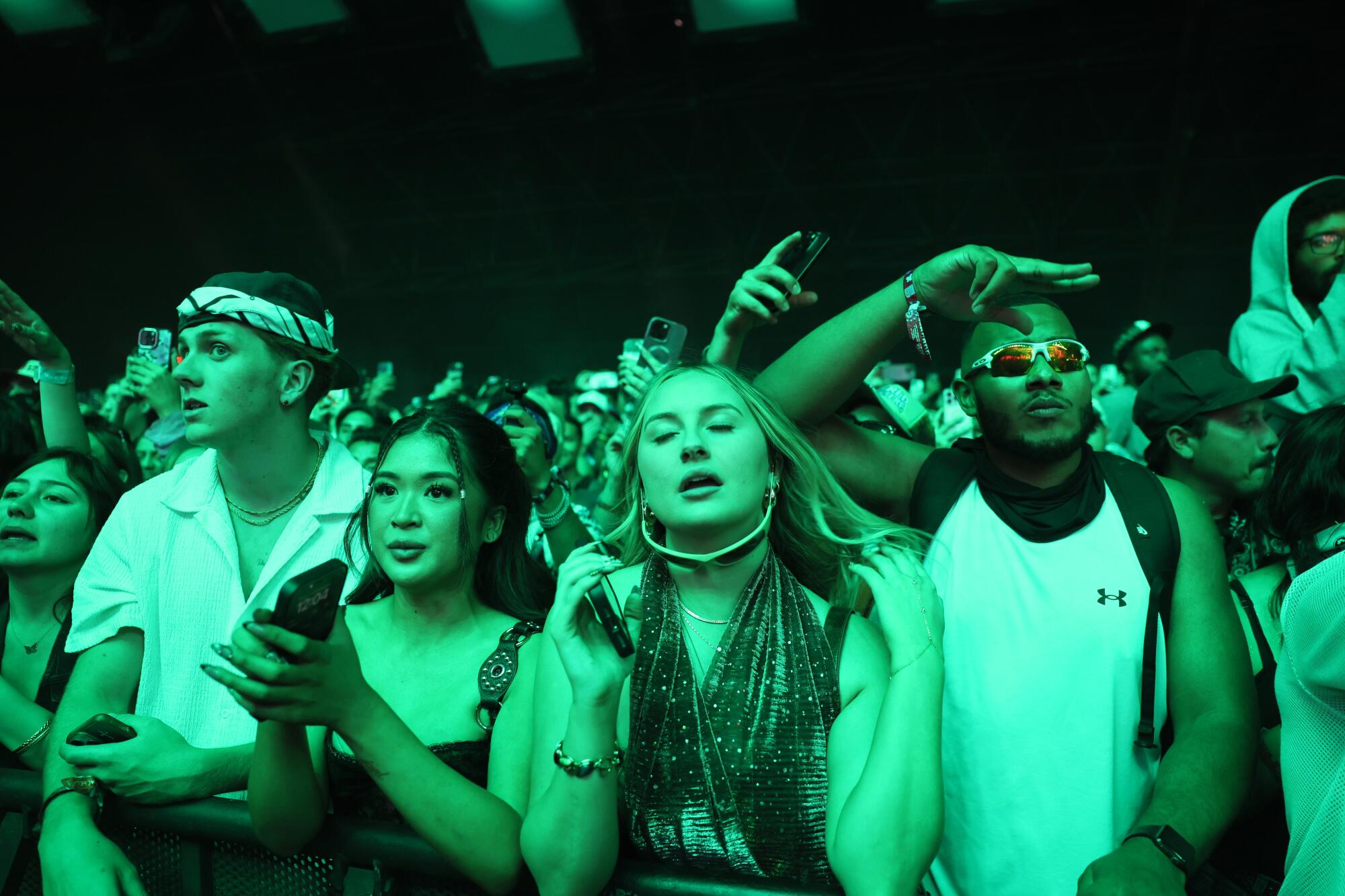Fans bathed in green light watching Mustard perform