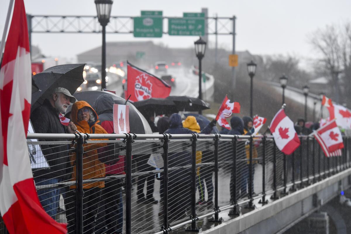 Protesters bearing Canadian flags gather near a U.S.-Canada border crossing.