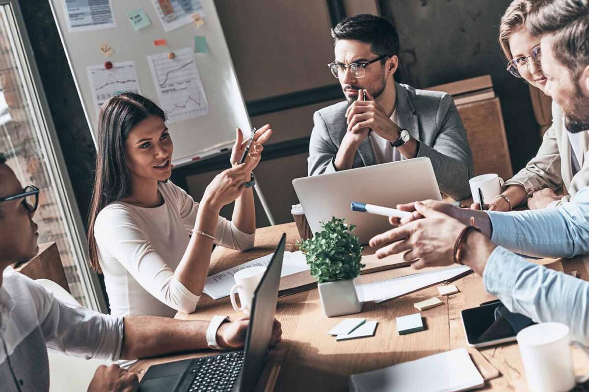 Group of confident young people discussing business while having meeting in the office
