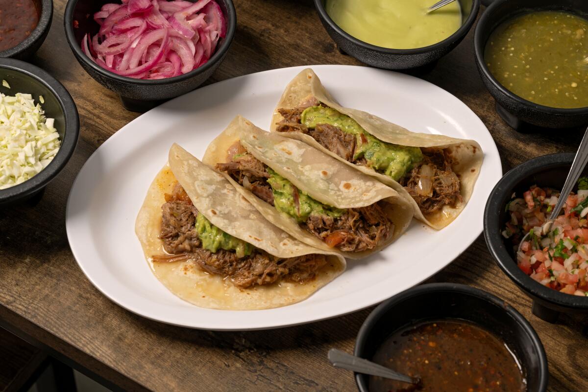 INGLEWOOD, CA - OCTOBER 22, 2024: A trio of the tacos de desebrada "Chikali Style" (with beans and guacamole) on house made flour tortillas at Asadero Chikali in Inglewood. (Ron De Angelis / For The Times)