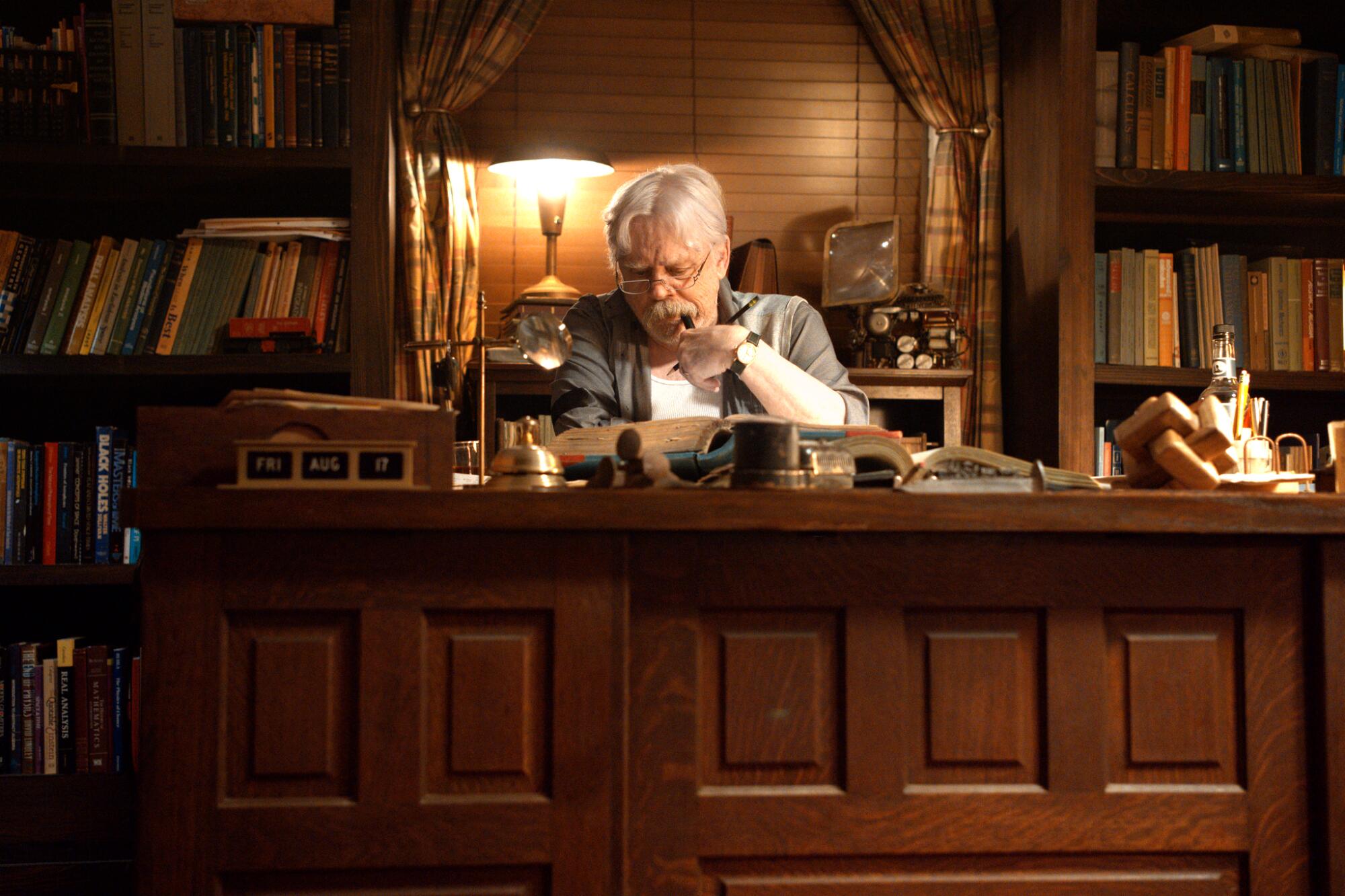 A man with gray hair works at a desk.